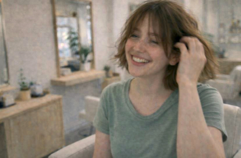 Je suis assise sur une chaise de salon de coiffure coréen, coiffure bob coréen légèrement floue, sourire naturel, ambiance lumineuse et minimaliste.