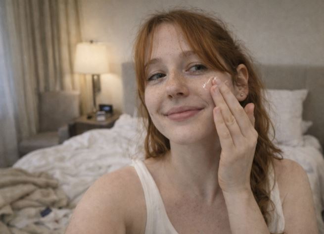 femme appliquant un sérum visage dans une chambre d’hôtel style naturel sans maquillage