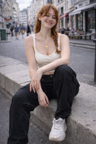 femme rousse freckles assise mur beton tenue streetwear pantalon cargo noir style coréen photo candid ville