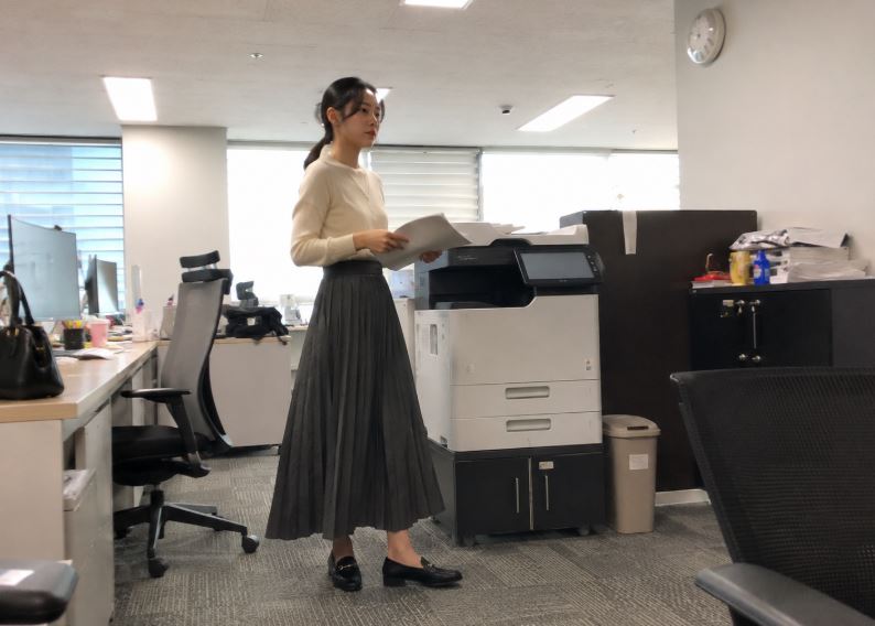 Femme asiatique en jupe longue plissée gris foncé dans un bureau à Séoul